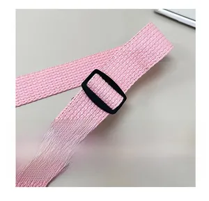 Gros plan sur la bandoulière en toile rose avec boucle de réglage en plastique noir