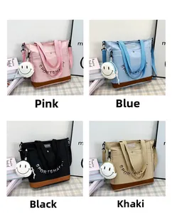 Grandi borse tote in tela nei colori rosa, blu, nero e kaki con ciondolo a forma di sorriso
