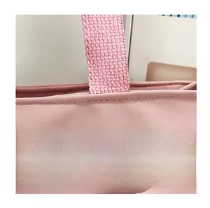 Détail du sac en toile rose montrant les coutures renforcées sur la poignée en nylon