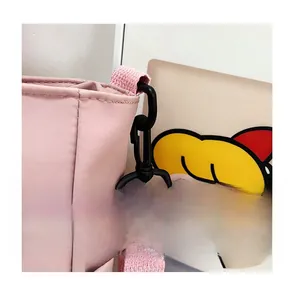 Détail du crochet rotatif en plastique noir et de la sangle tissée rose du sac en toile