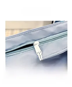 Dettaglio borsa in tessuto azzurro con cerniera metallica sicura e fibbia magnetica