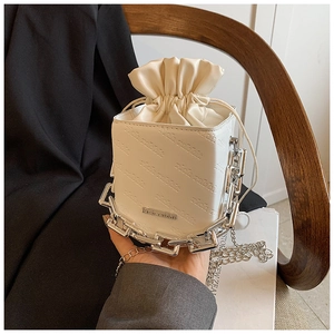Detail of white PU leather bucket bag featuring chain handle and rich rabbit embossing