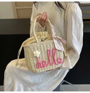 Detail of straw woven tote with hello embroidery, white flower and floral silk scarf