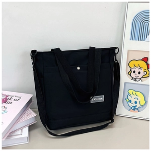 Détail du sac fourre-tout noir en toile avec étiquette FASHION et bandoulière