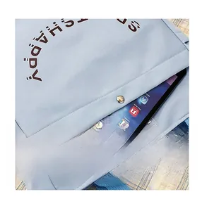 Primo piano della borsa tote in tela azzurra con tasca frontale e bottone in metallo