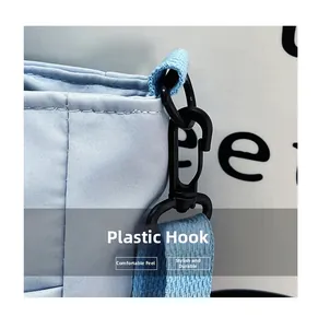Dettaglio del gancio rotante in plastica nera e della tracolla sulla borsa in nylon azzurro