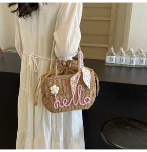 Detail of hand-woven straw bag with pink hello lettering and floral scarf decoration