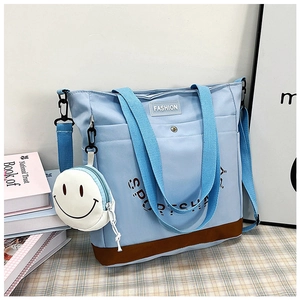 Dettaglio della borsa in tela celeste con base marrone e ciondolo smiley