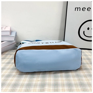 Dettaglio della base ampia e della striscia decorativa marrone su borsa blu chiaro