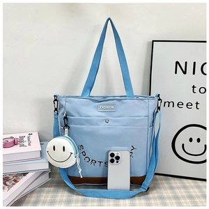 Dettaglio borsa shopper in tela blu con fondo marrone e portamonete con sorriso bianco