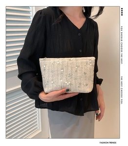 Detail of cream woven handbag with light green floral embroidery and zipper closure