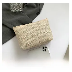 Detailed view of woven beige crossbody bag with floral embroidery and size comparison