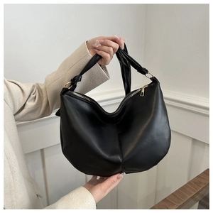 Close-up of black leather hobo bag with gold ring hardware and knotted strap details