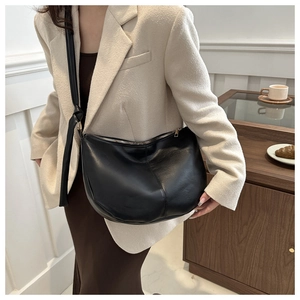 Detail of a black leather crescent hobo bag with gold zipper and minimalist stitching