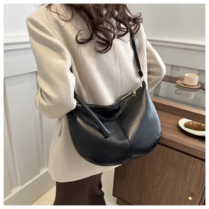 Detail of black faux leather crescent tote bag with smooth texture and central stitching