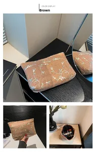 Detail of brown woven fabric pouch featuring delicate floral embroidery and zipper closure