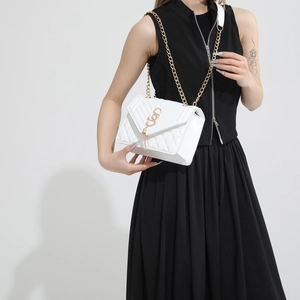 Quilted white shoulder bag with gold hardware and chain strap on a model in studio