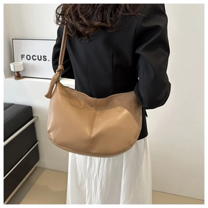 Detailed view of camel hobo bag with knotted strap worn by model in minimalist setting