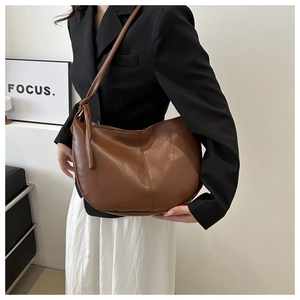 Detail of a brown crescent shoulder bag featuring stylish knot décor on the strap