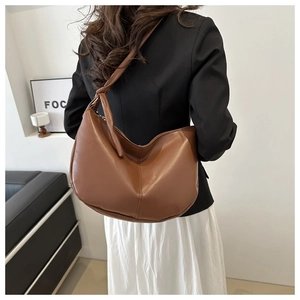 Brown PU leather crescent shoulder bag with knot detail shown from a side view on model