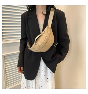 Dettaglio della borsa a mezzaluna beige con trama a pieghe su outfit moderno