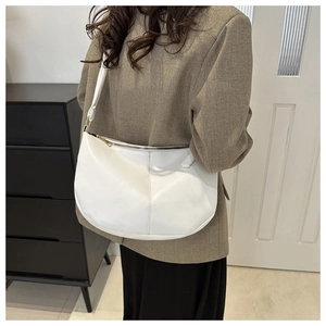 Detail of white crescent shoulder bag featuring smooth PU leather and gold zipper