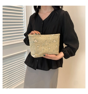 Close-up of woven crossbody bag featuring delicate white flower embroidery and leaf patterns