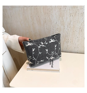 Detailed view of floral embroidery on grey woven fabric crossbody bag for women