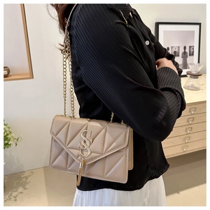 Close-up of beige quilted chain bag with gold metal logo and fringe detail on the side