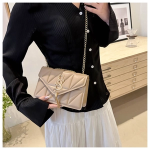 Detail of beige quilted flap bag with gold SS logo, fringe tassel and chain strap