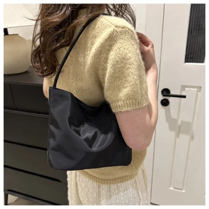 Detail of black satin underarm bag featuring onwards and upwards embroidered text