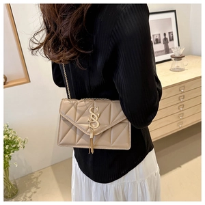 Detail of beige quilted shoulder bag with gold SS logo and elegant chain strap on model