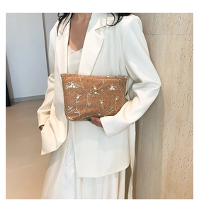 Detail of woven straw handbag featuring delicate white flower embroidery and leaf motifs