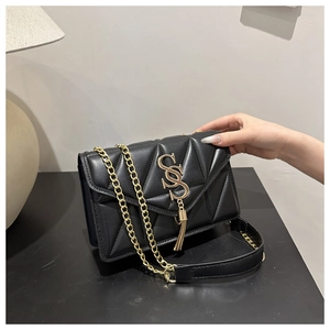 Detail of black quilted leather crossbody bag with gold S-logo and fringe tassel charm