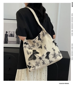 Detailed shot of white canvas tote featuring 3D black butterfly lace embroidery and texture