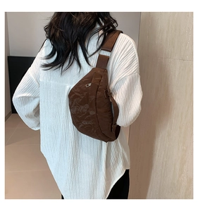 Dettaglio borsa a tracolla in nylon marrone stropicciato indossata su camicia bianca
