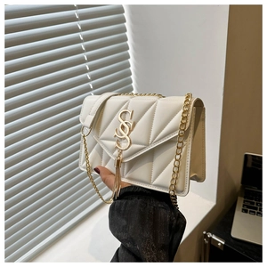 Detail of white quilted crossbody bag featuring golden S logo and long metal tassel