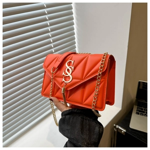 Detail of vibrant orange quilted leather bag with golden SS logo buckle and tassel
