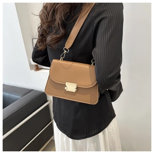Sac bandoulière moderne en cuir marron avec large bandoulière porté par un mannequin