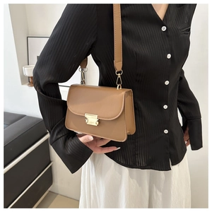 Sac bandoulière carré en cuir marron avec boucle dorée porté par un mannequin chic