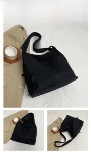 Detail of black floral lace embroidery on casual shoulder tote bag with wide strap