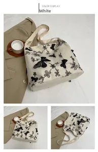 Detailed embroidery of black butterfly and flowers on white canvas underarm tote bag