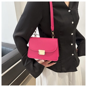 Détail du sac bandoulière rouge rose avec boucle dorée porté par un mannequin