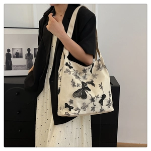 Detail view of 3D black butterfly embroidery on an off-white canvas shoulder bag