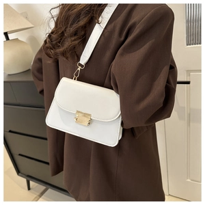 Détail d'un petit sac carré blanc avec boucle en métal doré et bandoulière large