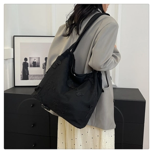 Detail view of exquisite 3D butterfly lace embroidery on a black canvas tote bag
