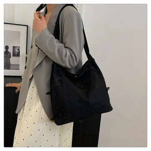 Detailed shot of black tote bag with 3D butterfly lace embroidery on premium fabric