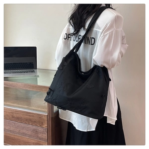 Detail of black tote bag featuring exquisite butterfly embroidery in a lifestyle setting
