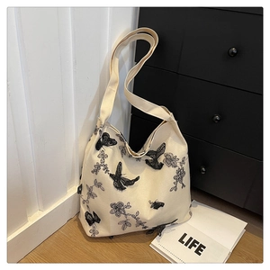 Close-up of intricate 3D black lace butterfly and floral embroidery on a canvas tote bag