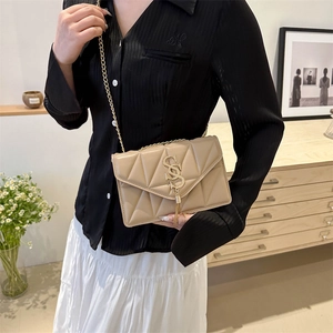 Beige quilted chain crossbody bag with gold hardware and tassel detail on model